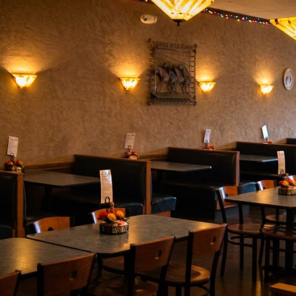 Empty restaurant dining room with booths and tables, warm lighting, and decorative wall art.