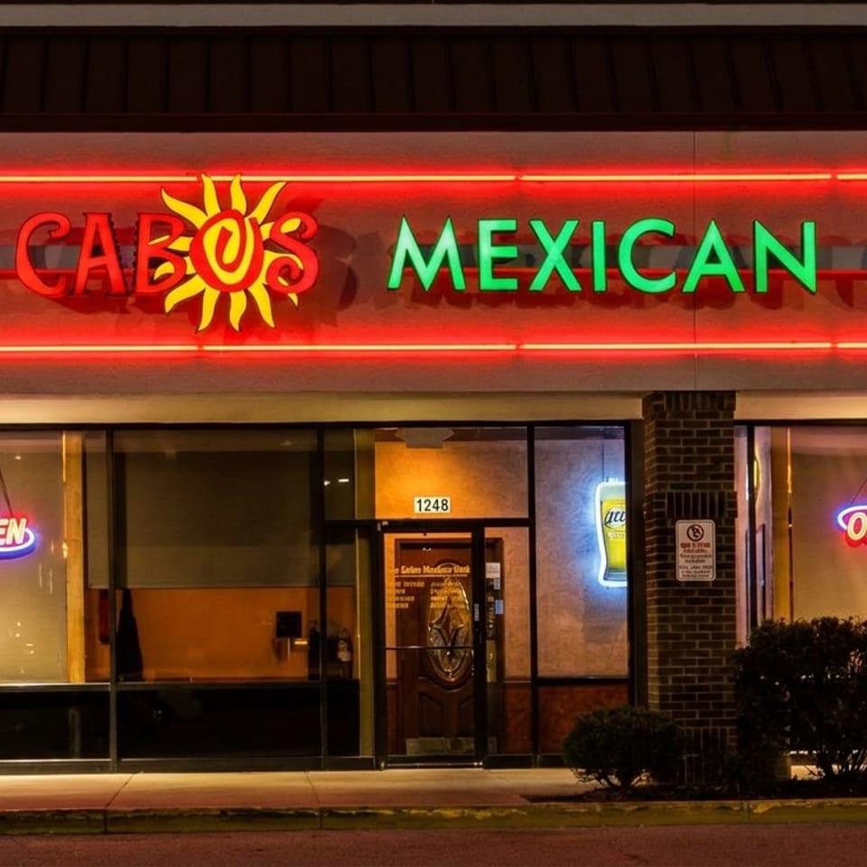 Exterior of Los Cabos Mexican Grill at night, with bright red and green neon signs.